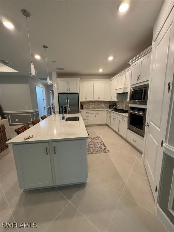 kitchen with sink, white cabinetry, appliances with stainless steel finishes, an island with sink, and pendant lighting