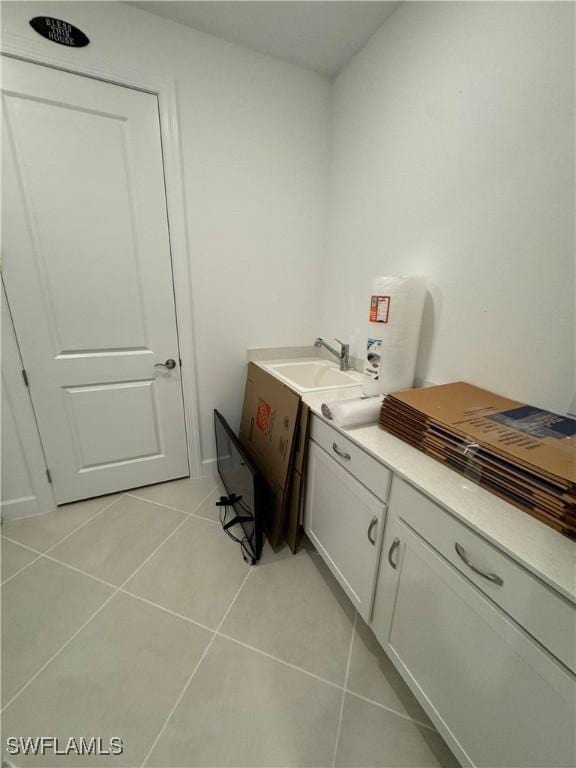 laundry area featuring sink and light tile patterned floors