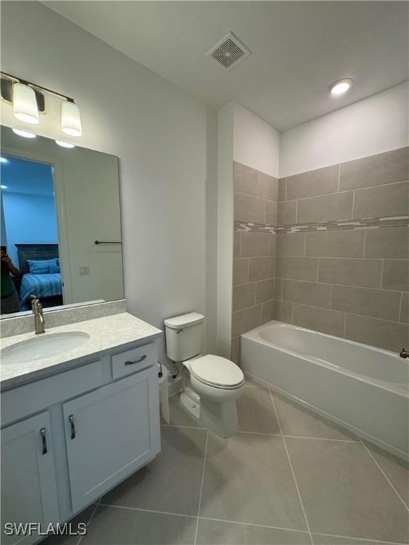 full bathroom with tile patterned flooring, tiled shower / bath, vanity, and toilet