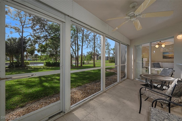 sunroom featuring ceiling fan and a water view