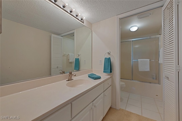 full bathroom featuring shower / bath combination with glass door, vanity, a textured ceiling, tile patterned floors, and toilet