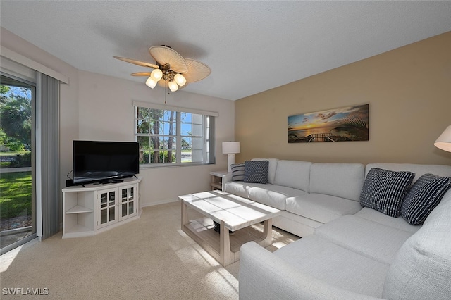 living room featuring ceiling fan, light colored carpet, and a textured ceiling