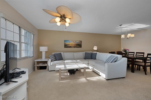 carpeted living room featuring ceiling fan with notable chandelier and a textured ceiling