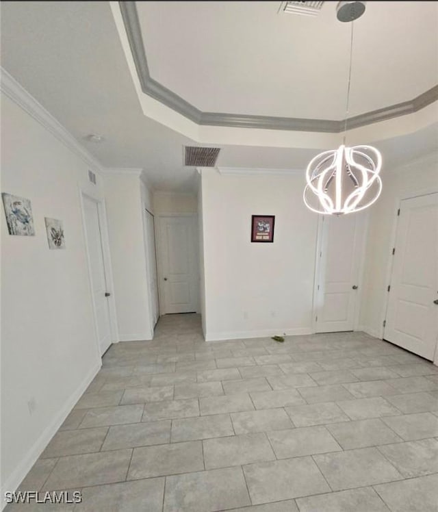 empty room featuring ornamental molding, a raised ceiling, and a notable chandelier