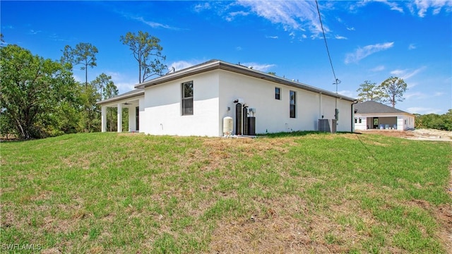 1420 Poinsettia Ave, Lehigh Acres, FL 33972 - rear view of house with central air condition unit, stucco siding, and a lawn