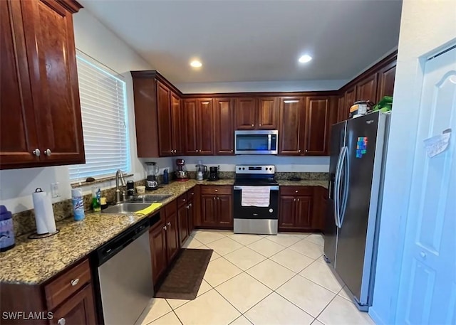 kitchen with light tile patterned floors, recessed lighting, stainless steel appliances, a sink, and light stone countertops