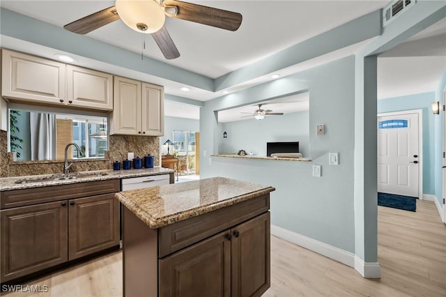 kitchen featuring tasteful backsplash, a kitchen island, light stone countertops, and sink