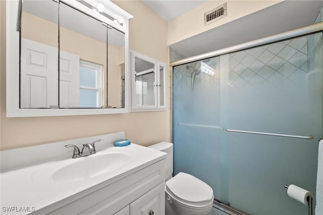 bathroom featuring vanity, a shower with door, and toilet