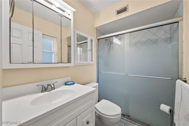 bathroom with vanity, a shower with shower door, and toilet