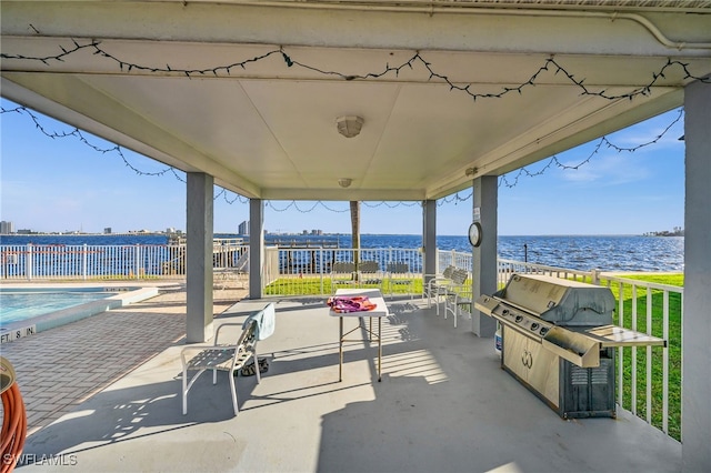 view of patio featuring exterior kitchen, a water view, a grill, and a community pool