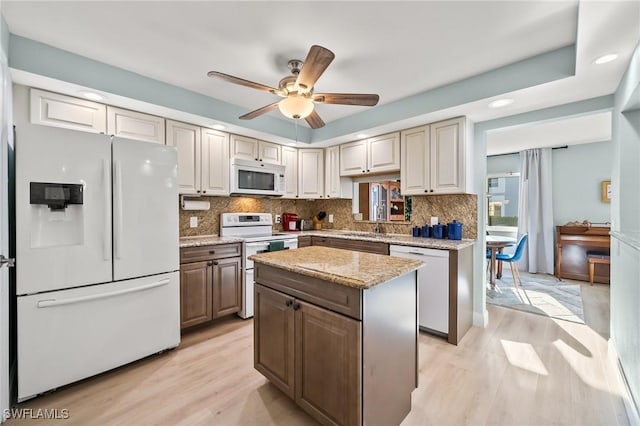 kitchen featuring white appliances, ceiling fan, a center island, decorative backsplash, and light wood-type flooring