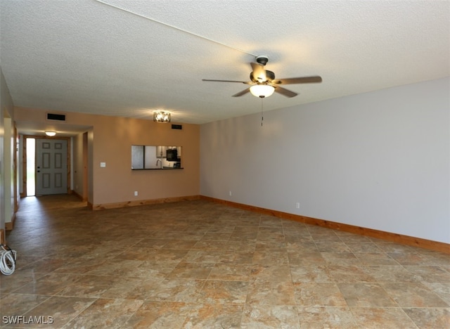 empty room featuring baseboards, visible vents, ceiling fan, and a textured ceiling