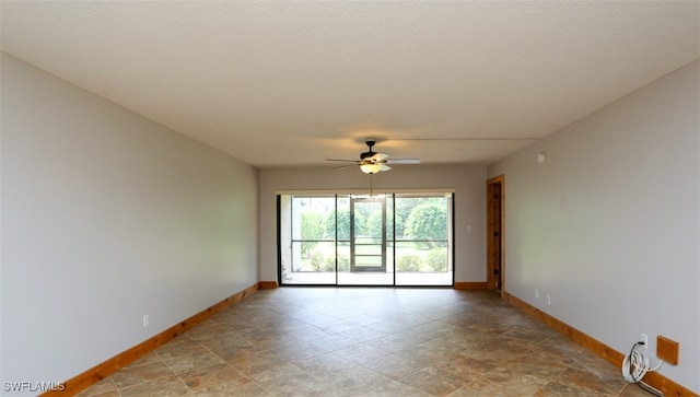 spare room featuring a ceiling fan and baseboards