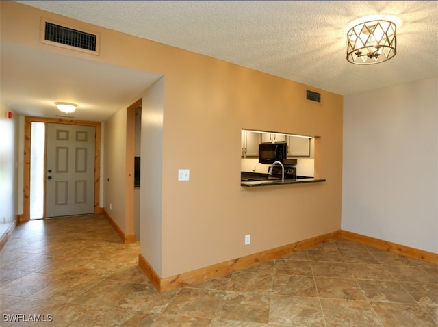 entrance foyer with a textured ceiling, visible vents, and baseboards