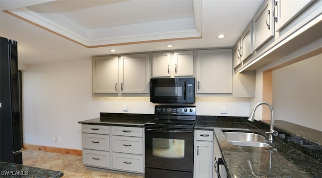 kitchen with a raised ceiling, gray cabinetry, a sink, dark stone countertops, and black appliances