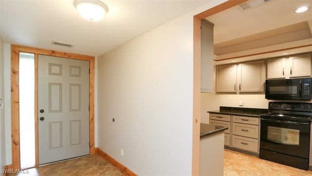 kitchen featuring dark stone counters, black appliances, visible vents, and baseboards