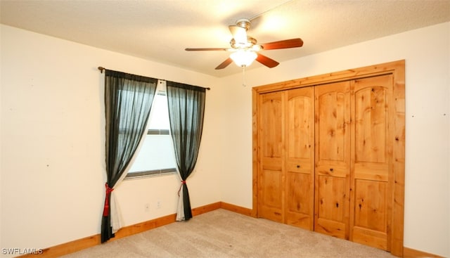 unfurnished bedroom featuring carpet floors, a closet, ceiling fan, and baseboards