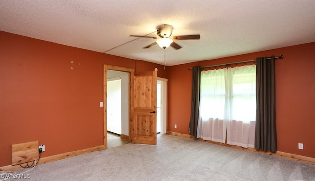 spare room featuring a ceiling fan, light carpet, a textured ceiling, and baseboards