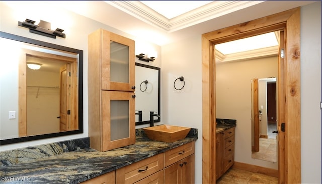 bathroom featuring a spacious closet, a raised ceiling, vanity, and crown molding