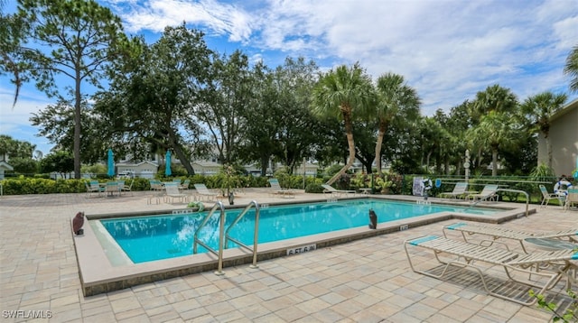 community pool with a patio area and fence