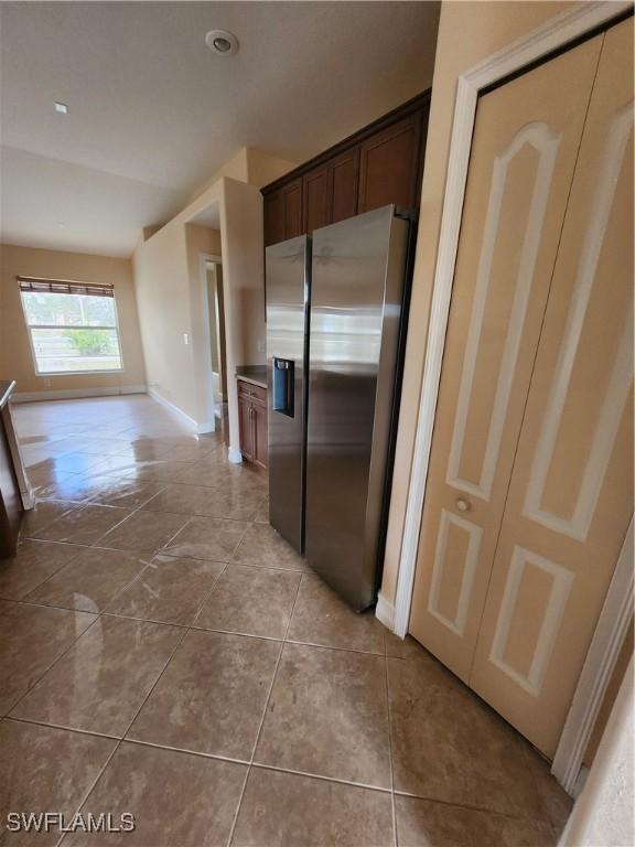 kitchen with tile patterned flooring, dark brown cabinets, and stainless steel refrigerator with ice dispenser