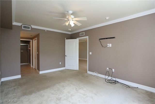 carpeted empty room featuring crown molding, a ceiling fan, visible vents, and baseboards