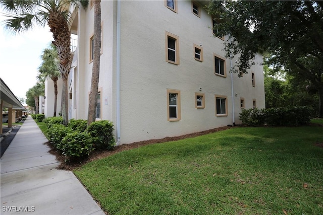 view of side of property featuring a lawn and stucco siding