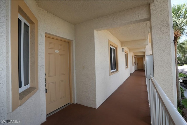 view of exterior entry with a balcony and stucco siding