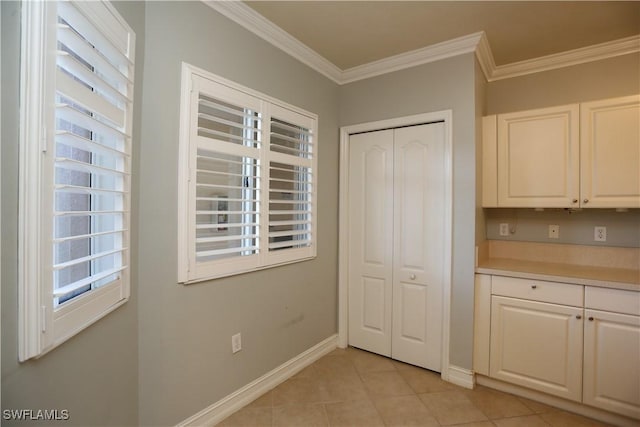 kitchen featuring light tile patterned floors, baseboards, light countertops, crown molding, and white cabinetry