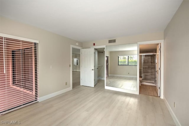 unfurnished bedroom with ensuite bathroom, light wood-type flooring, and a closet