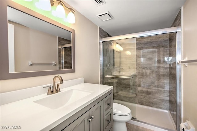 bathroom featuring vanity, an enclosed shower, and toilet