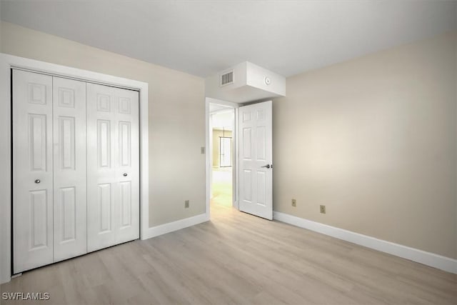 unfurnished bedroom with a closet and light wood-type flooring