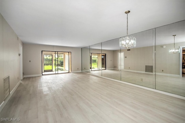 unfurnished room featuring an inviting chandelier and light wood-type flooring