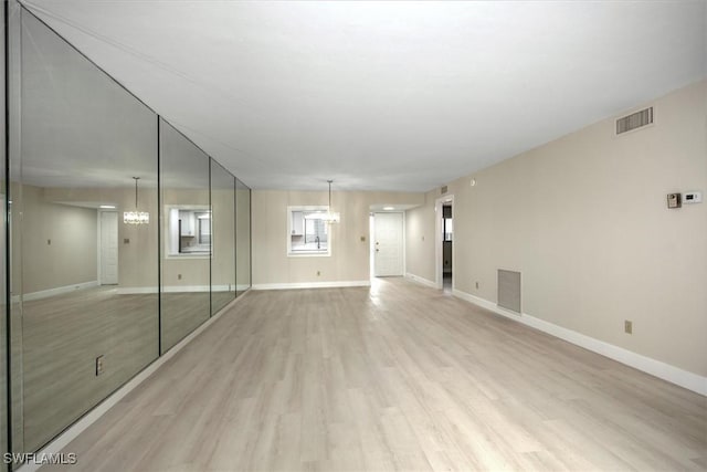 unfurnished living room with light hardwood / wood-style flooring and a notable chandelier