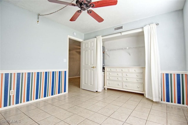 1100 Pondella Rd Unit 807, Cape Coral, FL 33909 - unfurnished bedroom with a wainscoted wall, a closet, tile patterned flooring, a ceiling fan, and baseboards