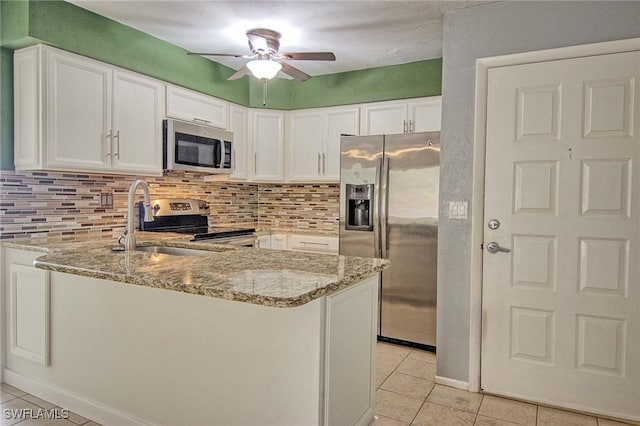 kitchen with stainless steel appliances, light stone countertops, kitchen peninsula, and white cabinets