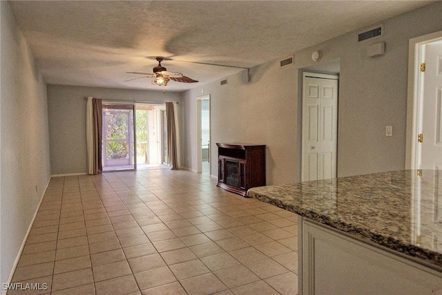1100 Pondella Rd Unit 807, Cape Coral, FL 33909 - unfurnished living room with a ceiling fan, light tile patterned flooring, a glass covered fireplace, baseboards, and a textured ceiling