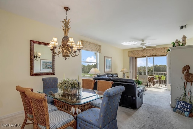 carpeted dining space with a healthy amount of sunlight and ceiling fan with notable chandelier