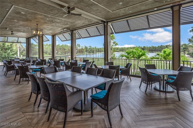 sunroom / solarium featuring a water view and a notable chandelier