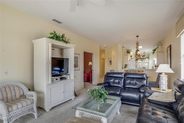 carpeted living room featuring ceiling fan with notable chandelier