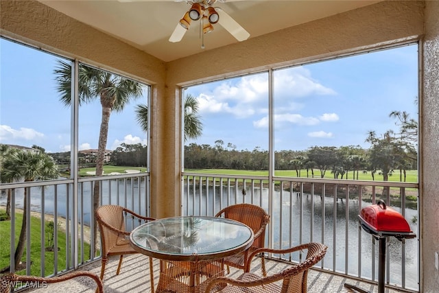 sunroom / solarium featuring ceiling fan and a water view