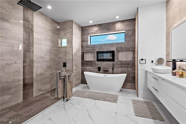 bathroom featuring independent shower and bath, vanity, and tile walls