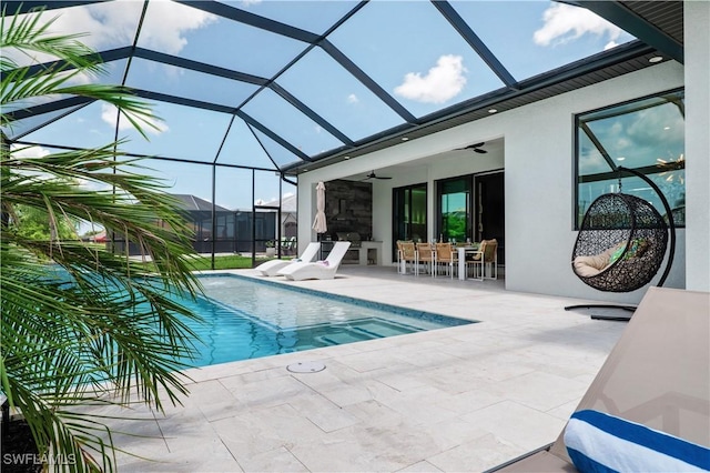 view of swimming pool with ceiling fan, glass enclosure, and a patio