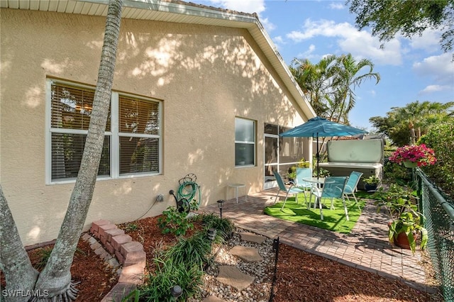 exterior space with a patio area, fence, and stucco siding