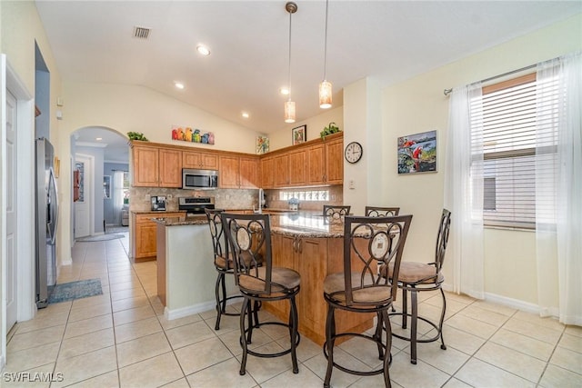 kitchen featuring stainless steel appliances, stone countertops, hanging light fixtures, and light tile patterned floors