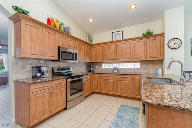 kitchen featuring stone counters, light tile patterned floors, stainless steel appliances, and a sink