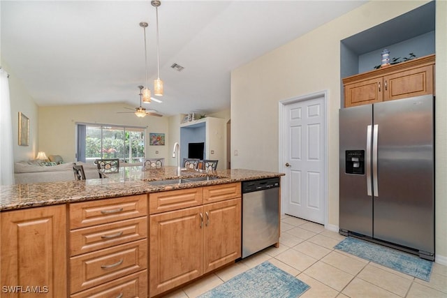 kitchen with appliances with stainless steel finishes, open floor plan, a sink, and light stone countertops