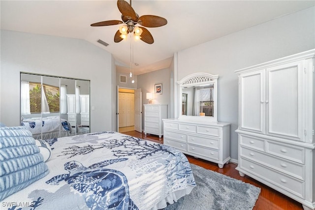 bedroom featuring lofted ceiling, dark wood-style floors, visible vents, and a ceiling fan