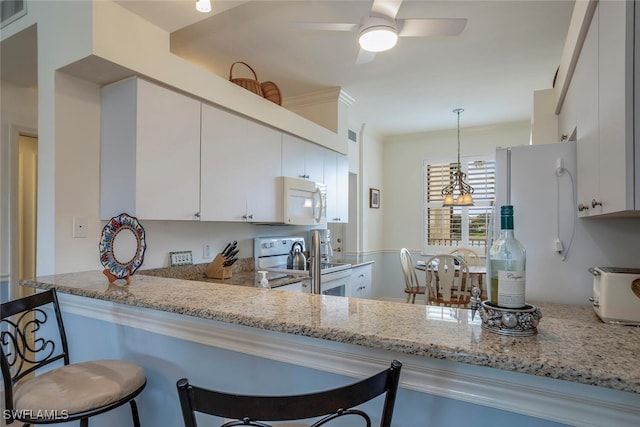 kitchen featuring light stone counters, kitchen peninsula, pendant lighting, white appliances, and white cabinets