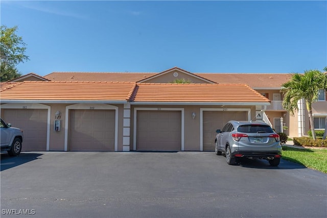 725 Saratoga Cir Unit A103, Naples, FL 34104 - view of front of home featuring stucco siding, community garages, and a tiled roof